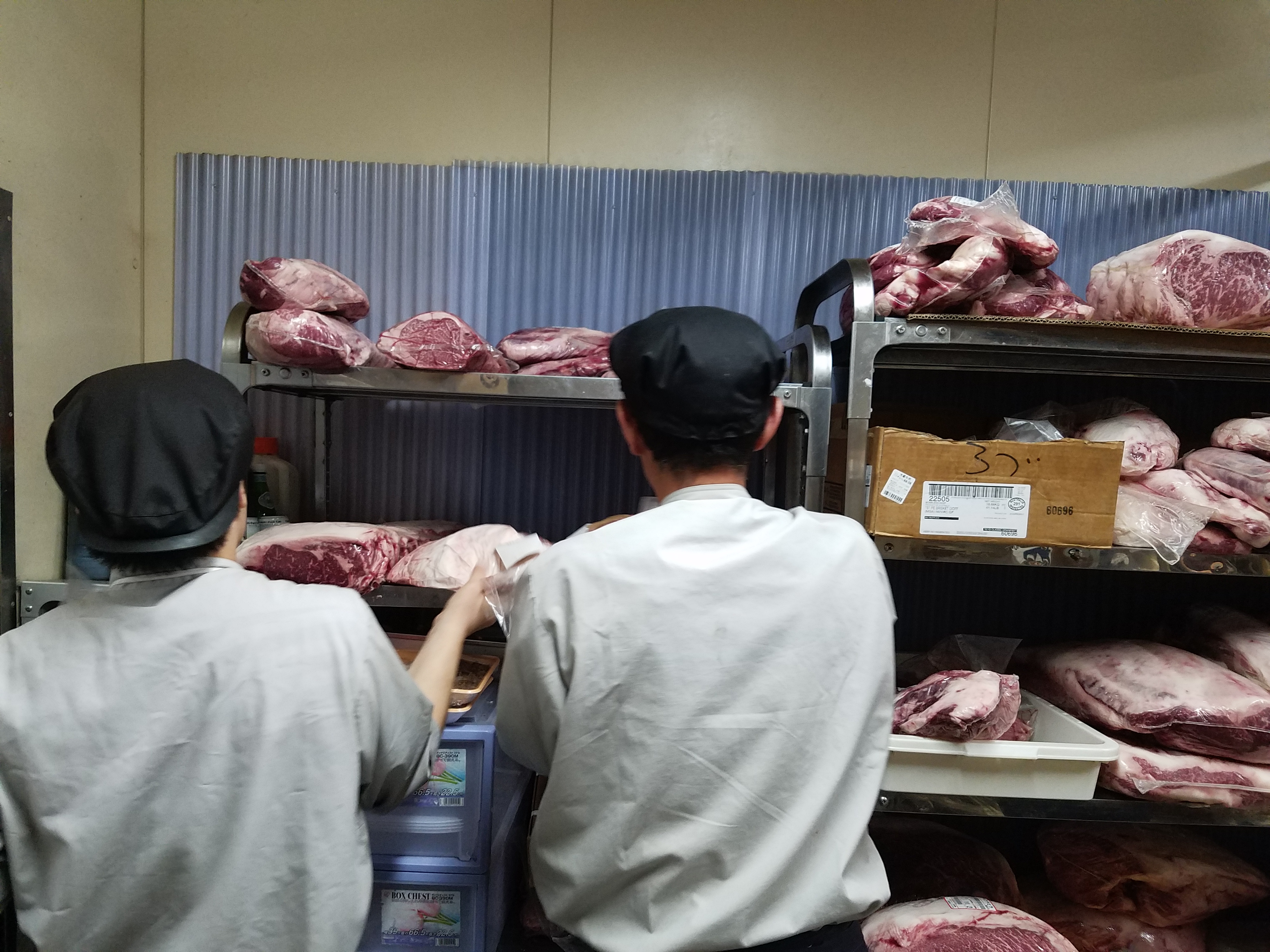 精肉作業中のスタッフ2名の後ろ姿